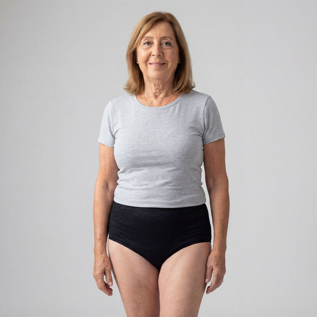 Femme portant une culotte absorbante noire taille haute pour incontinence féminine, solution lavable et discrète contre les fuites urinaires légères à modérées, en fibre de bambou confortable et sans odeur.