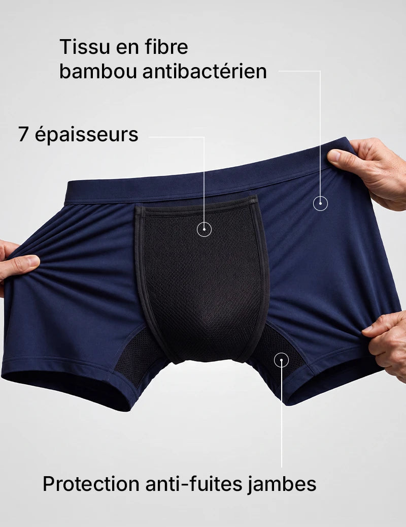 Mains écartant le boxer d'incontinence bleu marine pour montrer la zone absorbante à 7 épaisseurs.